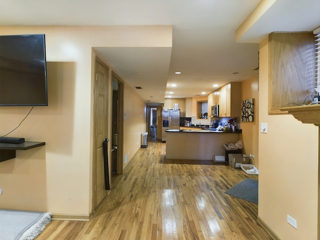 interior space with stainless steel appliances, light hardwood / wood-style floors, and kitchen peninsula