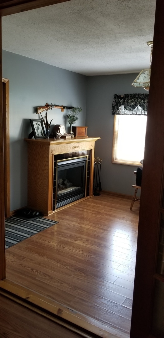 interior space with an inviting chandelier, a textured ceiling, light hardwood / wood-style floors, and a tile fireplace