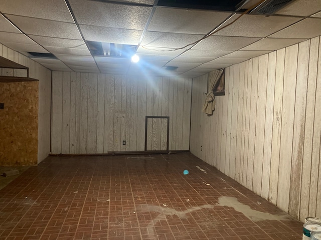 basement with wood walls and a drop ceiling