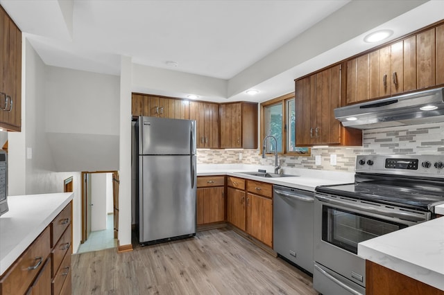 kitchen featuring light hardwood / wood-style floors, tasteful backsplash, sink, range hood, and appliances with stainless steel finishes