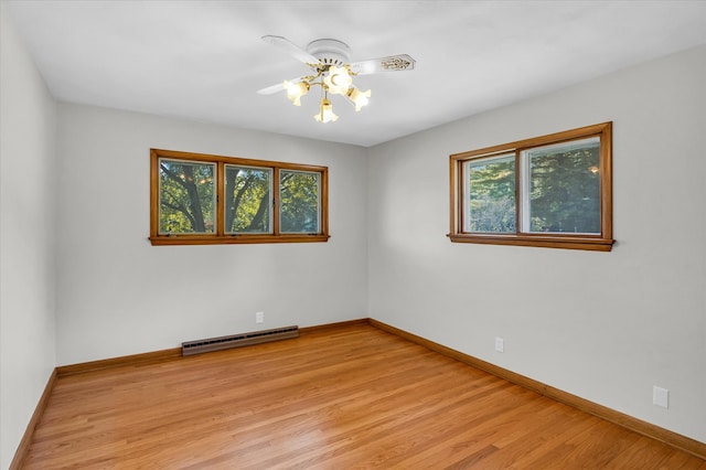 empty room featuring light hardwood / wood-style floors, a baseboard heating unit, ceiling fan, and a wealth of natural light