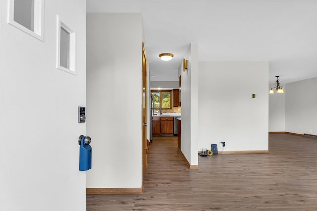 hall with wood-type flooring and a chandelier