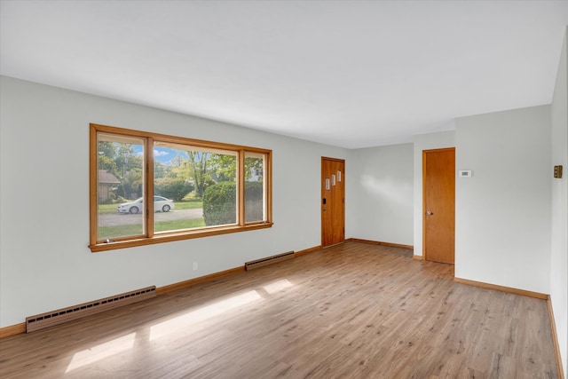 spare room with baseboard heating and light hardwood / wood-style flooring