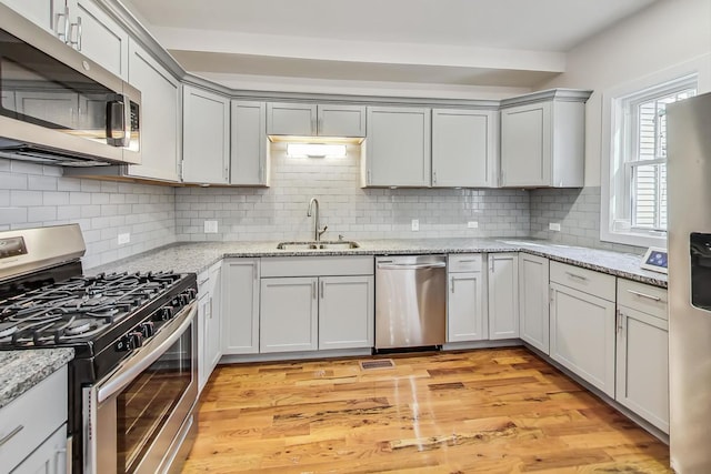 8251 S E End Ave, Chicago, IL 60617 - kitchen with appliances with stainless steel finishes, backsplash, light wood-style floors, gray cabinets, and light stone countertops