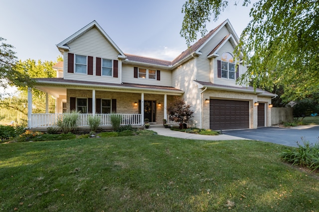 view of front of house with a porch, a front yard, and a garage