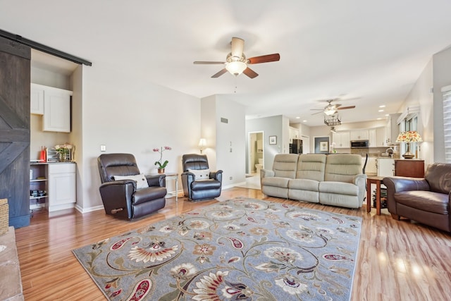 living room featuring light wood-type flooring, a barn door, and ceiling fan