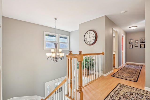 hallway with hardwood / wood-style flooring and a notable chandelier