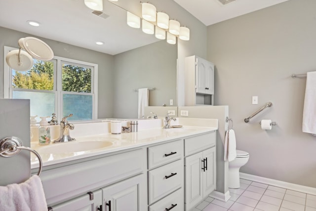 bathroom with toilet, vanity, and tile patterned flooring