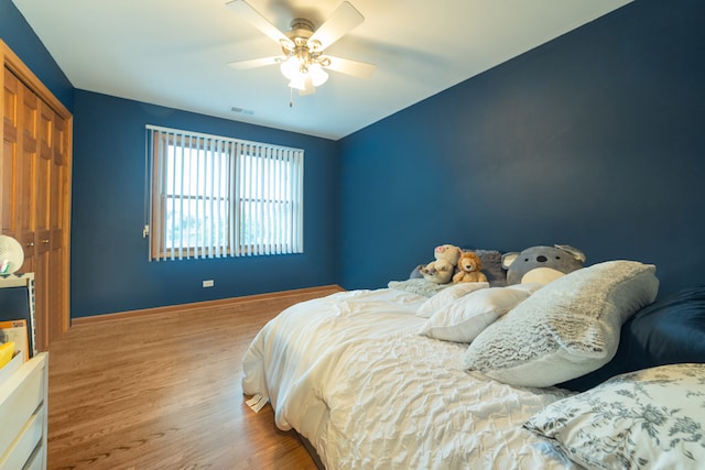 bedroom with light wood-type flooring, ceiling fan, and a closet