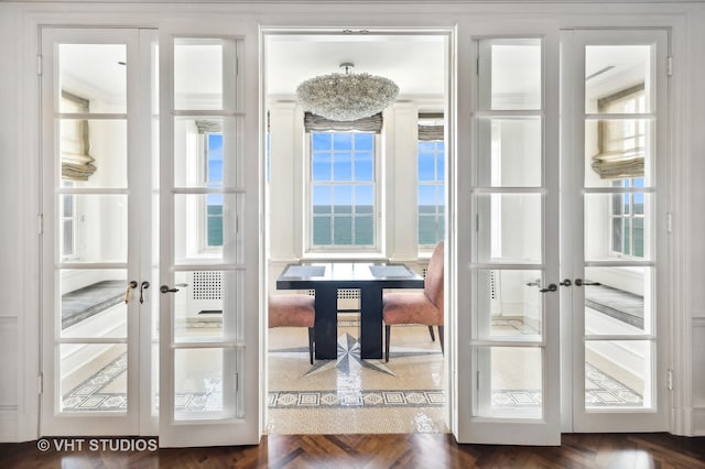 entryway featuring ornamental molding, a chandelier, french doors, and dark parquet flooring