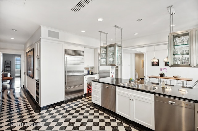 kitchen with appliances with stainless steel finishes, white cabinets, sink, and decorative light fixtures