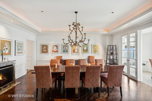 dining area featuring a tray ceiling, a notable chandelier, a premium fireplace, crown molding, and dark parquet flooring