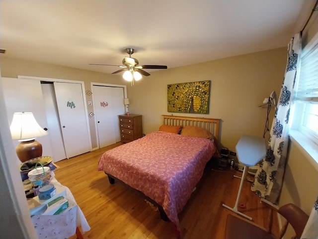 bedroom with ceiling fan, hardwood / wood-style floors, and multiple closets