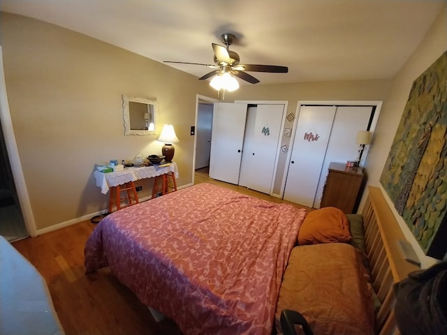 bedroom featuring multiple closets, wood-type flooring, and ceiling fan