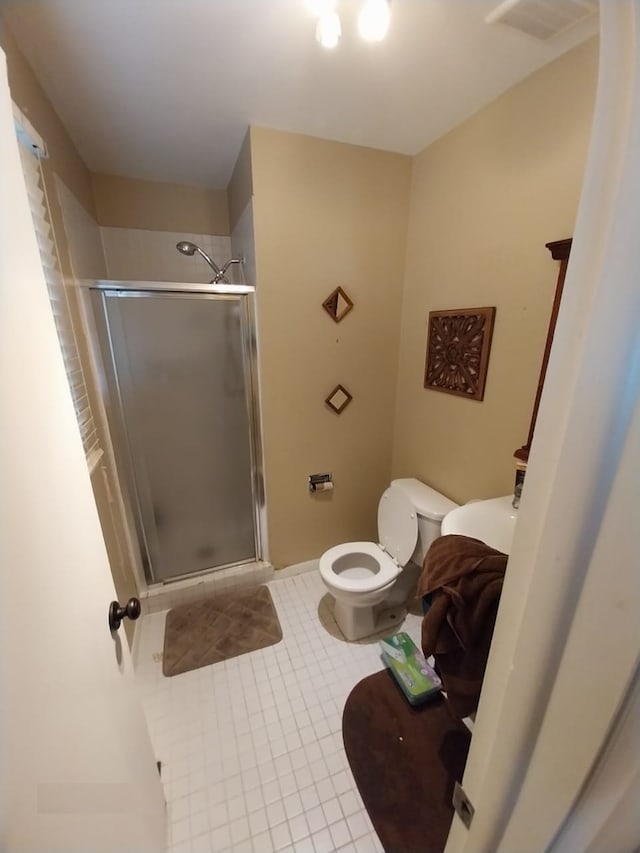 bathroom with toilet, a shower with door, and tile patterned floors