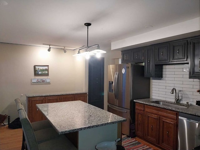 kitchen featuring pendant lighting, wood-type flooring, a center island, sink, and appliances with stainless steel finishes