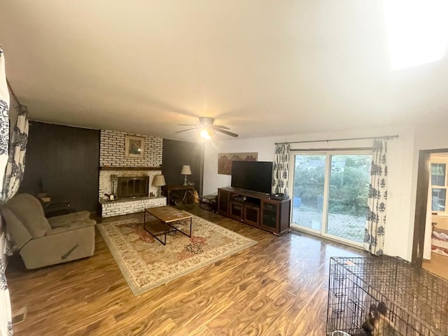 living room featuring ceiling fan, hardwood / wood-style flooring, and a fireplace