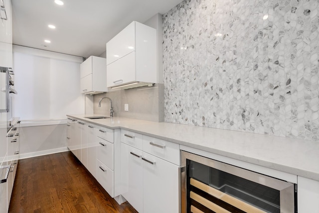 kitchen with dark hardwood / wood-style floors, beverage cooler, sink, decorative backsplash, and white cabinetry