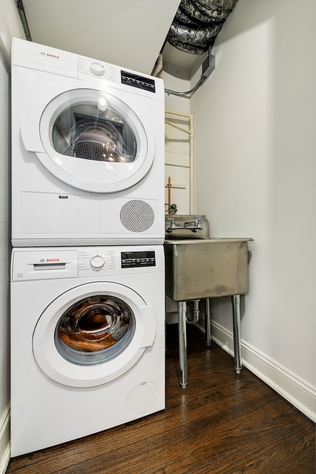 clothes washing area with stacked washer and clothes dryer and dark hardwood / wood-style floors