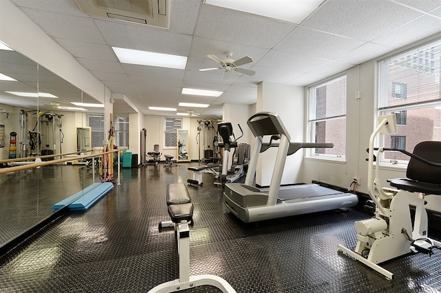 exercise room featuring a paneled ceiling, ceiling fan, and a wealth of natural light