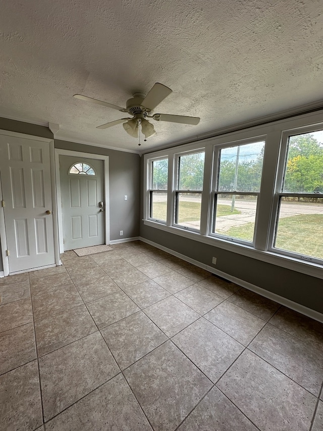 tiled empty room with ceiling fan and a textured ceiling