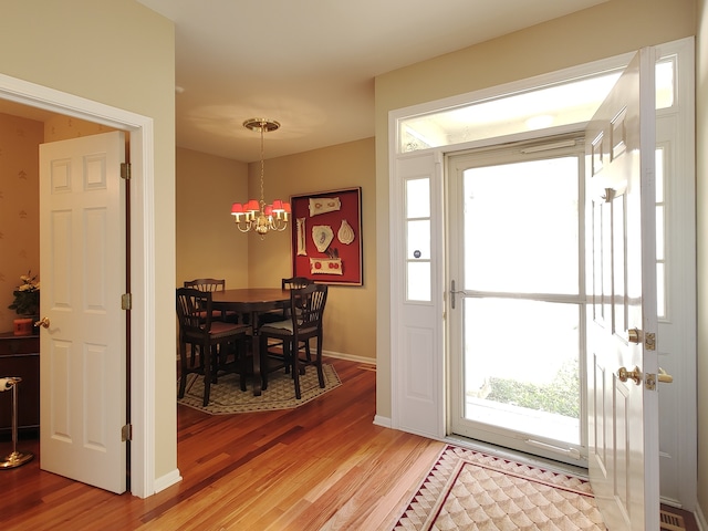 foyer entrance with an inviting chandelier and wood-type flooring