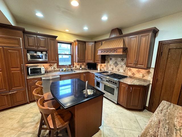 kitchen featuring a center island, custom range hood, stainless steel appliances, sink, and dark stone counters