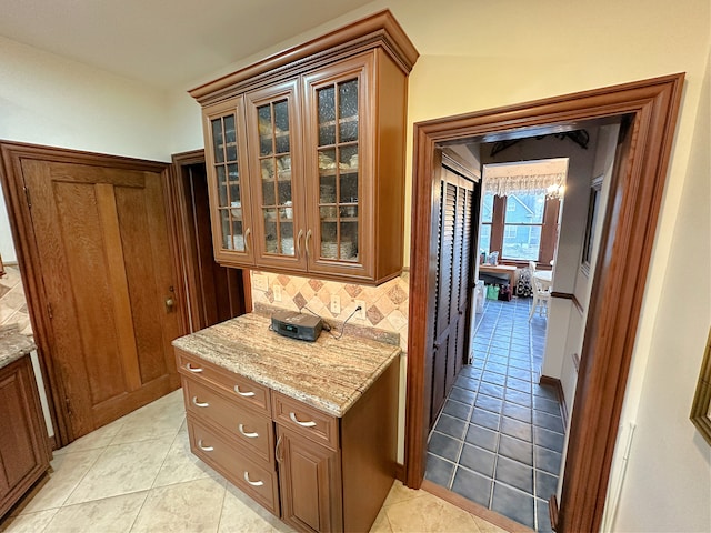 kitchen with light stone countertops, backsplash, and light tile patterned flooring