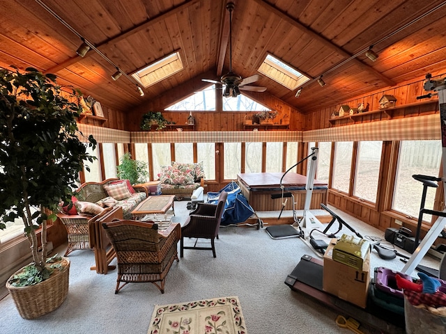 interior space with wood ceiling, vaulted ceiling with skylight, ceiling fan, and wooden walls