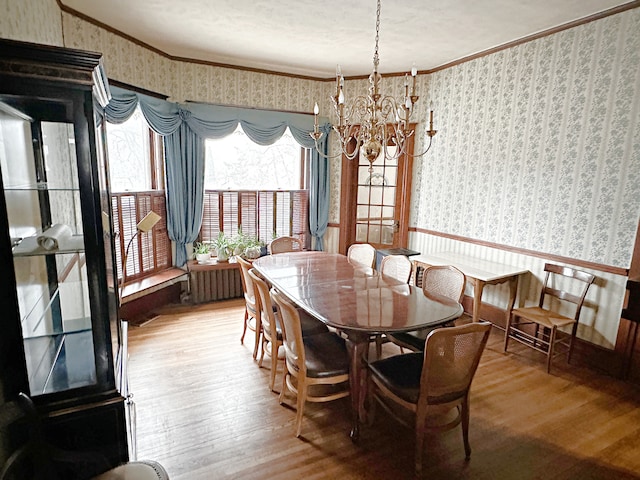 dining room with ornamental molding, radiator, wood-type flooring, and a notable chandelier