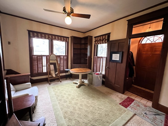 carpeted foyer with ceiling fan and ornamental molding