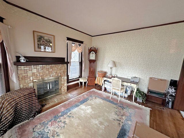 living room featuring hardwood / wood-style flooring, a tiled fireplace, and ornamental molding