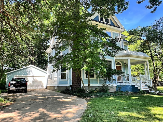 view of front of house with an outdoor structure, a garage, a front yard, and covered porch