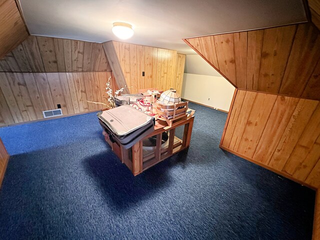 game room with carpet flooring, vaulted ceiling, and wooden walls