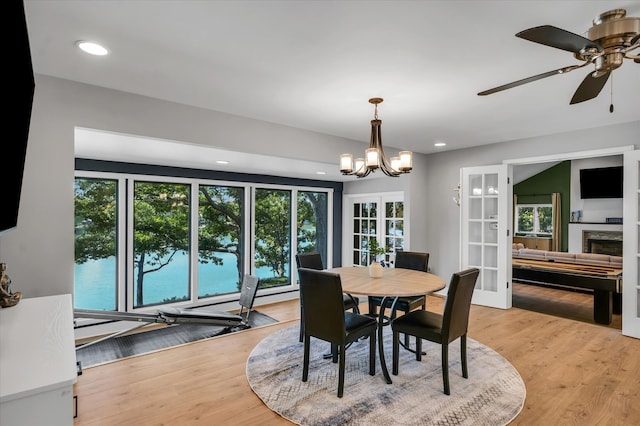 dining area featuring light hardwood / wood-style flooring and ceiling fan with notable chandelier