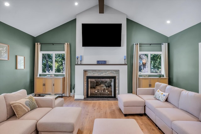 living room with high vaulted ceiling, light wood-type flooring, and a healthy amount of sunlight