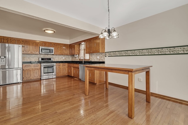 kitchen featuring pendant lighting, light wood-type flooring, appliances with stainless steel finishes, and a chandelier