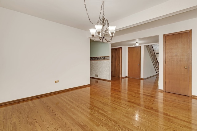 spare room featuring light hardwood / wood-style flooring and a notable chandelier