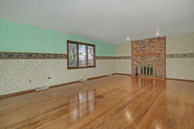 unfurnished living room featuring a brick fireplace and hardwood / wood-style flooring