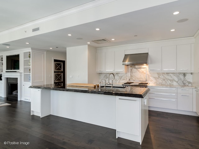 kitchen with sink, wall chimney range hood, and white cabinetry