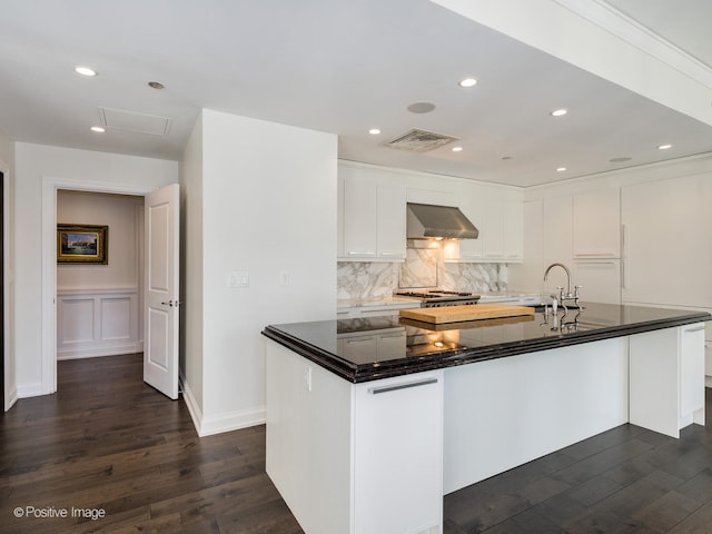 kitchen with wall chimney range hood, tasteful backsplash, sink, dark hardwood / wood-style floors, and white cabinetry