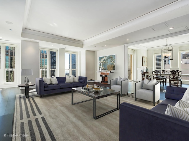 living room featuring a raised ceiling, crown molding, and a notable chandelier