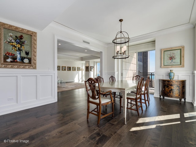 dining area with an inviting chandelier, crown molding, and dark hardwood / wood-style flooring