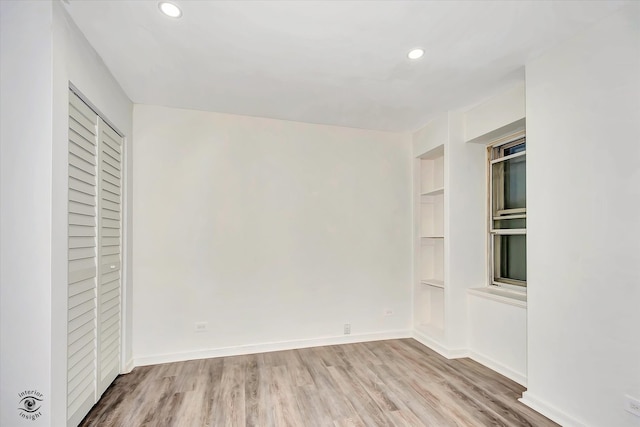 empty room with built in shelves and hardwood / wood-style floors