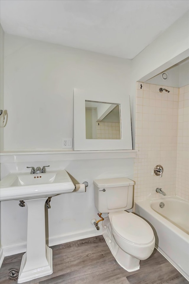 bathroom with hardwood / wood-style flooring, tiled shower / bath, and toilet