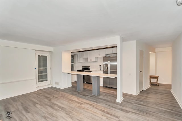 kitchen featuring sink, gray cabinets, appliances with stainless steel finishes, a kitchen breakfast bar, and light hardwood / wood-style floors