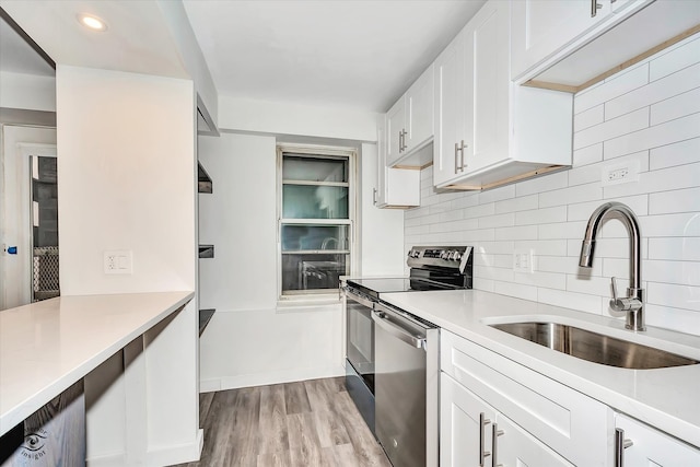 kitchen with white cabinets, sink, tasteful backsplash, light hardwood / wood-style flooring, and stainless steel appliances