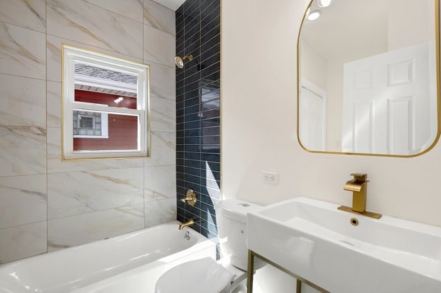 full bathroom featuring vanity, tiled shower / bath combo, and toilet