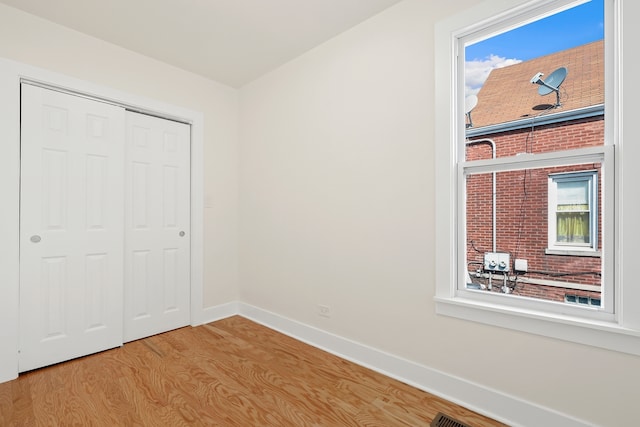 unfurnished bedroom featuring a closet, light hardwood / wood-style flooring, and multiple windows