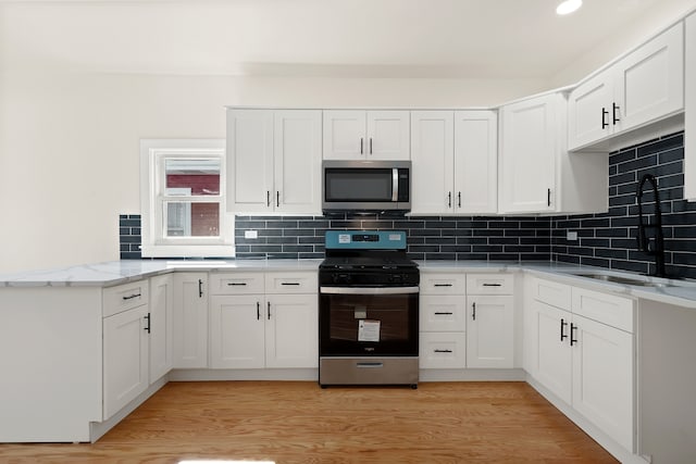 kitchen with white cabinets, light wood-type flooring, and stainless steel appliances